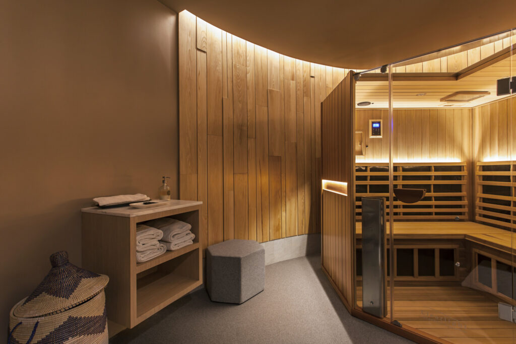 Person relaxing in modern infrared sauna with wooden interior